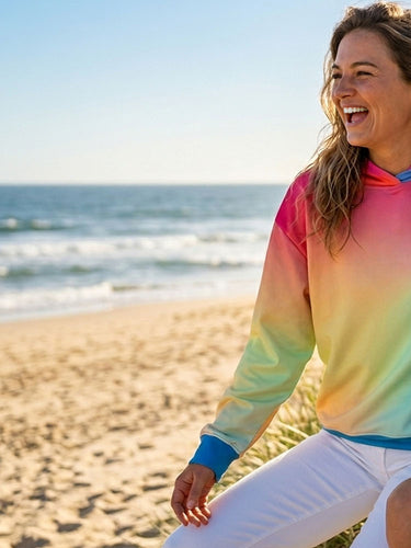 Zwei Frauen sitzen am Strand mit bunten Hoodies und Sweatshirts